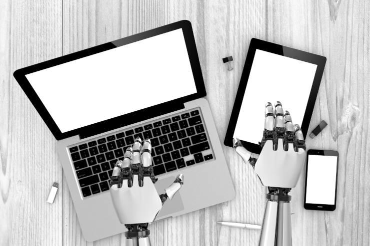 Mani di un robot che usano pc e tablet: IA personificata