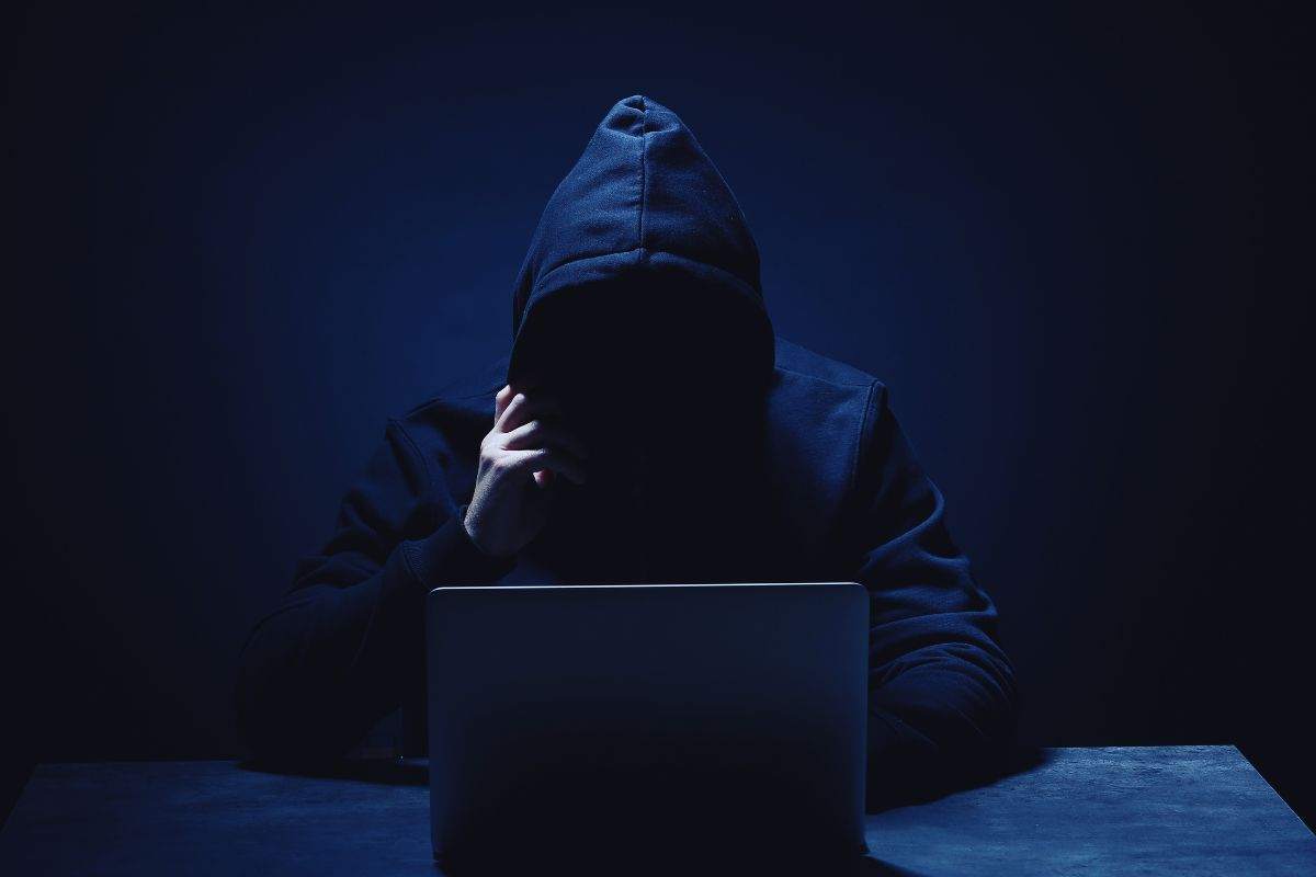 Uomo incappucciato che utilizza un PC portatile