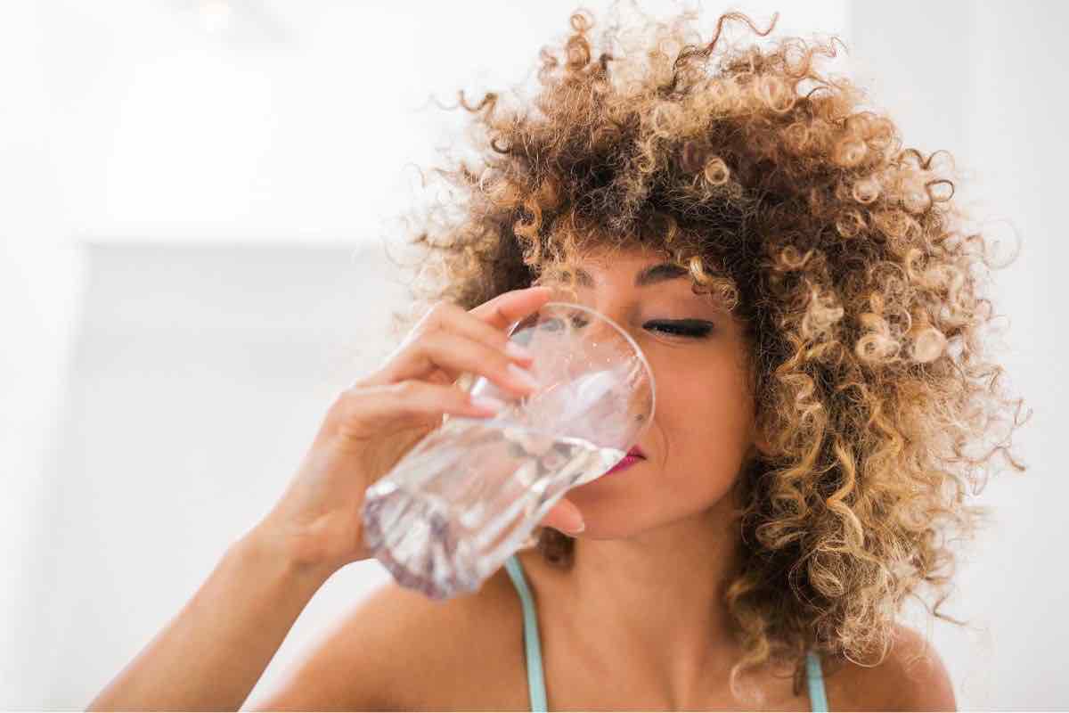 Donna che beve un bicchiere di acqua